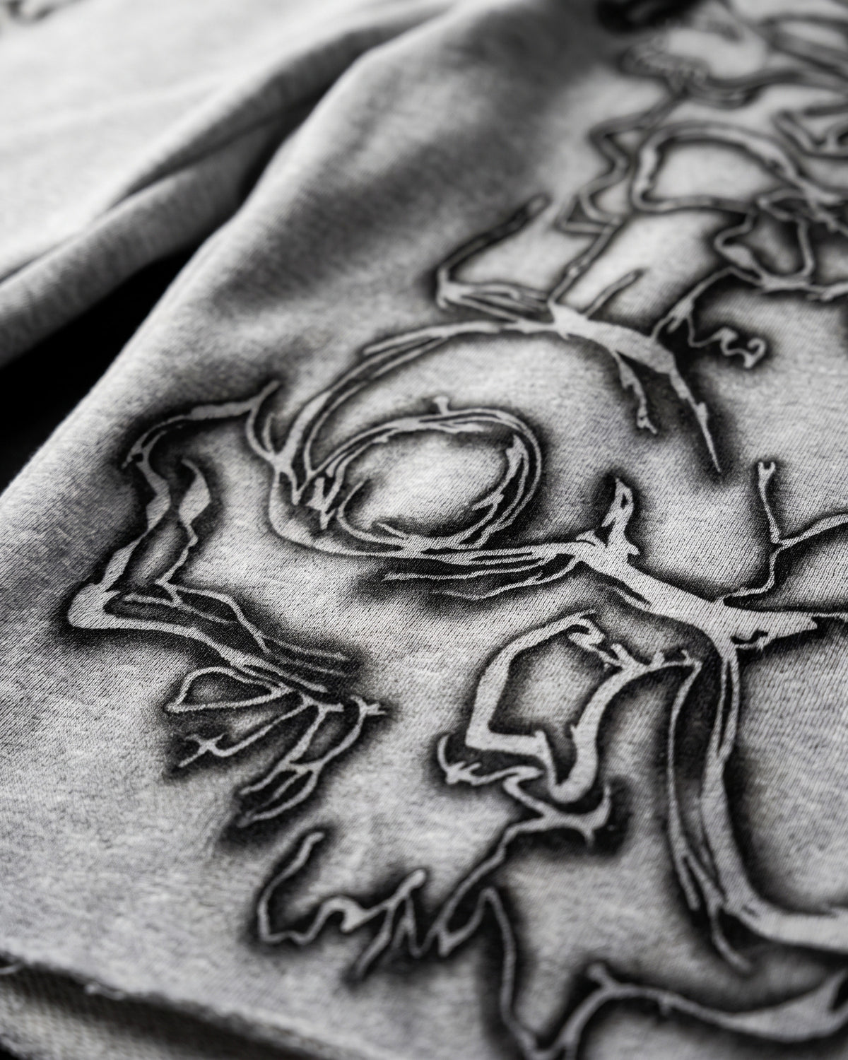 ATO GREY AIRBRUSH SWEAT JORTS – close-up of the airbrushed skull outline
