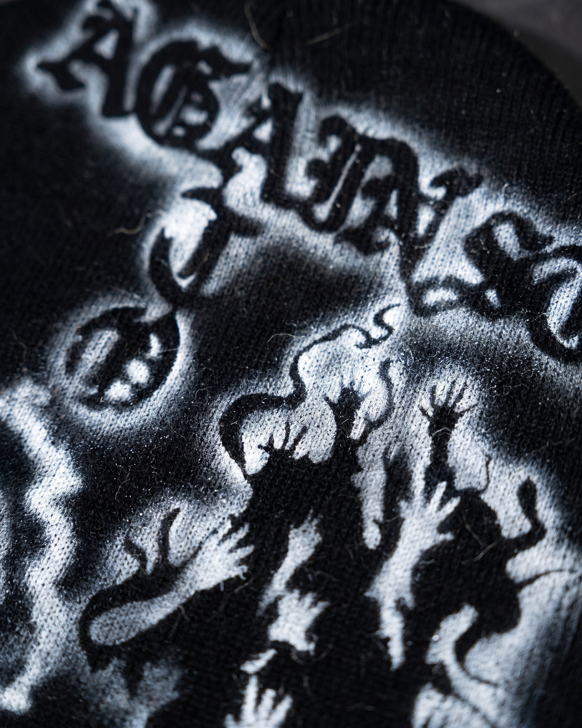ATO AIRBRUSH Black Skeleton Beanie – close-up of the "Against" lettering and reaching-hands artwork