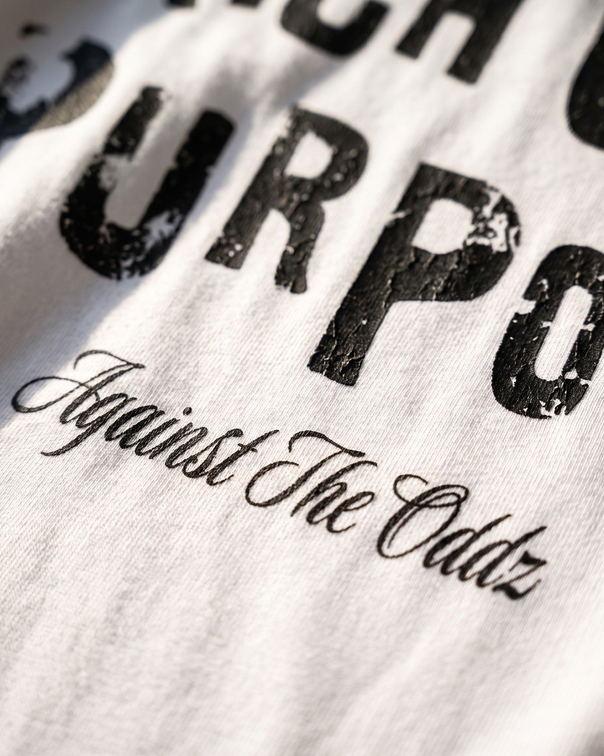 ATO RICH OFF PURPOSE TEE – close-up of the "Against The Oddz" script